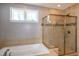 Enclosed shower with seamless glass door and neutral tile surround, plus a soaking tub with tile surround at 1820 Yates Wheel Way, Raleigh, NC 27606