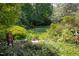 Serene backyard featuring lush landscaping, a gnome statue, and vibrant flower beds, perfect for relaxation at 19 Oak Dr, Durham, NC 27707