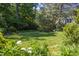Lush backyard with mature trees, flowering bushes, and a charming building at 19 Oak Dr, Durham, NC 27707