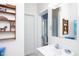 Bright bathroom featuring a white vanity with shelving unit, mirror, and a partially visible blue-striped shower curtain at 19 Oak Dr, Durham, NC 27707