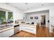 Bright white kitchen with hardwood floors, stainless steel appliances, and a view into the dining room at 19 Oak Dr, Durham, NC 27707