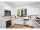 A bright white kitchen is lit by recessed lights and includes stainless steel appliances and a large window at 19 Oak Dr, Durham, NC 27707