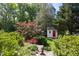 Quaint backyard shed with a red door, surrounded by lush greenery and vibrant flowers, creating a serene retreat at 19 Oak Dr, Durham, NC 27707