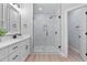 Modern bathroom with dual vanity, tiled shower, glass enclosure, and light wood floors at 249 Rawhide Dr, Louisburg, NC 27549