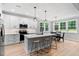 Modern kitchen with white cabinets, an island with bar stools, and a dining area at 249 Rawhide Dr, Louisburg, NC 27549