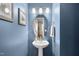 Charming half bath featuring a pedestal sink, oval mirror and light fixture on a blue painted wall at 322 Brier Crossings Loop, Durham, NC 27703