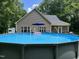 Backyard above-ground pool featuring a deck, lounge chairs, and a backdrop of green trees at 4072 Mackenzie Dr, Haw River, NC 27258