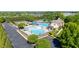 Aerial view of a community pool featuring a splash pad, slide, and lounge area surrounded by lush landscaping at 4116 Argyle Trl, Burlington, NC 27215