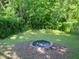 A peaceful backyard area featuring a fire pit, lush green grass, and mature trees at 4205 Woodlawn Dr, Raleigh, NC 27616