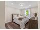 Neutral bedroom with wood floor, bright window, white trim, and dark wood nightstand at 4902 Cedar Glen Dr, Durham, NC 27713