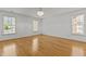 An expansive, light-filled bedroom with gleaming hardwood floors, a chandelier, and multiple windows is move-in ready at 5619 Bennettwood Ct, Raleigh, NC 27612