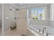 Relaxing primary bathroom featuring a glass shower, soaking tub, and a large window at 5619 Bennettwood Ct, Raleigh, NC 27612