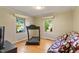 Cozy bedroom featuring hardwood floors, two windows, a patterned sofa, and a treadmill for exercise at 708 Mills St, Raleigh, NC 27608
