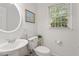 Bathroom featuring a round mirror, pedestal sink, and toilet at 7213 St Ledger Dr, Raleigh, NC 27613