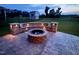 Night view of backyard with stone fire pit and built-in seating, highlighted by soft lighting, on a stamped concrete patio at 808 Buckner Ct, Fuquay Varina, NC 27526