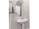 A simple powder room features a pedestal sink, an oval mirror, and neutral wall paint at 808 Buckner Ct, Fuquay Varina, NC 27526