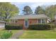 Charming brick home featuring a manicured lawn with lush shrubbery and a welcoming blue front door at 809 Leon St, Durham, NC 27704
