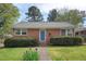 Charming brick home featuring a manicured lawn with lush shrubbery and a welcoming blue front door at 809 Leon St, Durham, NC 27704