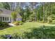Lush backyard featuring green lawn, mature trees, and garden beds, offering a private outdoor oasis at 8304 Epping Forest Way, Wake Forest, NC 27587