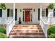 Inviting front porch with brick steps, classic white railings, and a vibrant red front door with decor at 8304 Epping Forest Way, Wake Forest, NC 27587