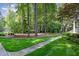 Well-maintained front yard with lush green lawn, mature trees, and inviting walkway to the house at 8304 Epping Forest Way, Wake Forest, NC 27587