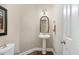 Cozy powder room with a pedestal sink, decorative mirror, and neutral wall color at 8304 Epping Forest Way, Wake Forest, NC 27587