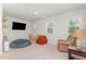 Carpeted bonus room with natural light, comfortable seating, TV, and shelving at 8616 Deep Elm Dr, Wake Forest, NC 27587