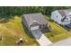 An aerial view of a well-manicured property with gray siding, brick accents, attached garage, and long driveway at 94 Shooting Star Ln, Clayton, NC 27520
