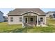 Charming covered patio with outdoor seating, a grill, and attractive landscaping in the backyard at 94 Shooting Star Ln, Clayton, NC 27520