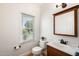 Well-lit bathroom featuring a wooden vanity, dark fixtures, and a view to the outside at 104 Ludstone Ct, Cary, NC 27513