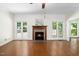 Inviting living room featuring hardwood floors, a cozy fireplace, and large windows offering picturesque backyard views at 104 Ludstone Ct, Cary, NC 27513
