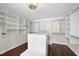 Large walk-in closet with custom shelving, center island, and wood flooring at 10825 Rondeau Woods Ct, Raleigh, NC 27614