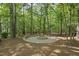 Outdoor stone fire pit with built-in stone seating surrounded by a canopy of trees at 10825 Rondeau Woods Ct, Raleigh, NC 27614