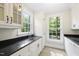 Mudroom with sink, white cabinets, black granite countertops, and two windows at 10825 Rondeau Woods Ct, Raleigh, NC 27614