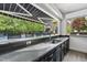 Outdoor kitchen with sink and bar that opens to the pool and seating area at 10825 Rondeau Woods Ct, Raleigh, NC 27614