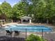 Large in-ground pool, pool house, and fenced in yard surrounded by mature landscaping at 10825 Rondeau Woods Ct, Raleigh, NC 27614