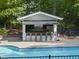 View of the pool house and pool area surrounded by a brick deck and wrought iron fence at 10825 Rondeau Woods Ct, Raleigh, NC 27614