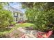 Lush backyard with mature trees, manicured lawn, deck, and patio with red Adirondack chairs at 109 Hogan Glen Ct, Chapel Hill, NC 27516
