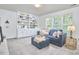 Inviting living area with blue sofa, ottoman, built-in shelving, and natural light from large windows at 109 Hogan Glen Ct, Chapel Hill, NC 27516