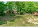 A spacious and treed backyard with a wooden fence and grass, partially shaded by mature trees at 1095 Vauxhall Dr, Apex, NC 27502