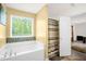 Bathroom featuring a large tub with tile detail next to a large window providing natural light and an open door to the toilet at 11 Mamie Ferguson Dr, Lillington, NC 27546