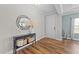 Welcoming entryway with wood floors, decorative mirror, console table with decor, and a pristine white door at 116 Chaseford Ct, Holly Springs, NC 27540