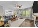 Spacious living room featuring multiple windows, a comfortable gray sofa, and a glimpse of the kitchen at 116 Chaseford Ct, Holly Springs, NC 27540