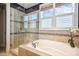 Luxurious bathroom featuring a soaking tub, glass-enclosed shower, and serene garden view at 120 Mearleaf Pl, Holly Springs, NC 27540