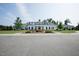 Beautiful white clubhouse exterior with manicured landscaping and a circular driveway at 120 Mearleaf Pl, Holly Springs, NC 27540