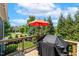 Outdoor deck with an umbrella and grill, surrounded by lush greenery at 120 Mearleaf Pl, Holly Springs, NC 27540