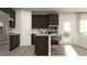 Modern kitchen with dark wood cabinets, stainless steel appliances, a breakfast bar with seating, and bright natural light at 1552 Bright Coral Trl, Wendell, NC 27591