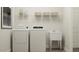 Well-lit laundry room with white washer and dryer, a sink, and wire shelving for organized storage at 1552 Bright Coral Trl, Wendell, NC 27591