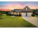 Charming exterior elevation of the home with a well-manicured lawn and a two-car garage under a sunset sky at 17 Kaki Ct, Selma, NC 27576