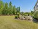 Landscaped backyard featuring mature trees, firepit, outdoor seating, and well-maintained lawn at 1701 Bodwin Ln, Apex, NC 27502